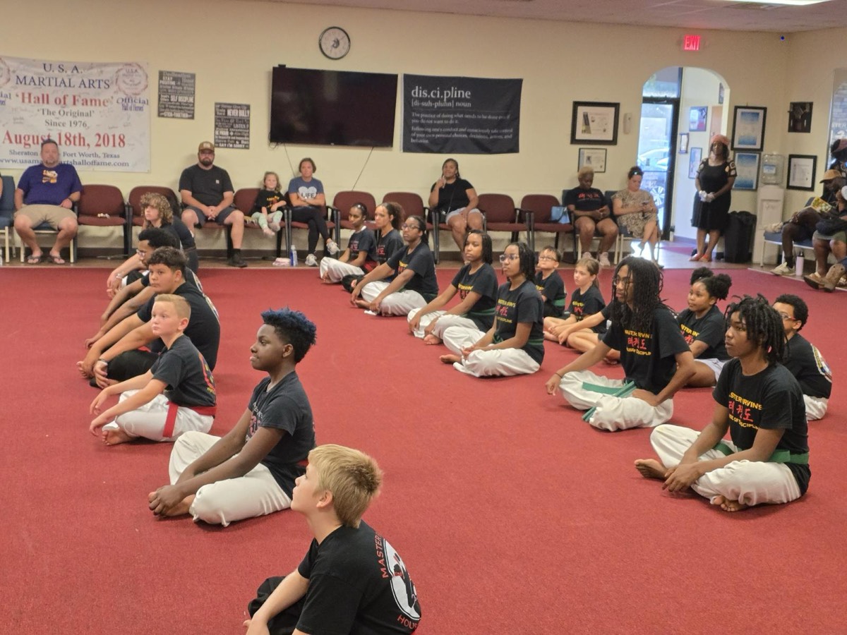 A class seated on the floor beneath the school's Hall of Fame banner.