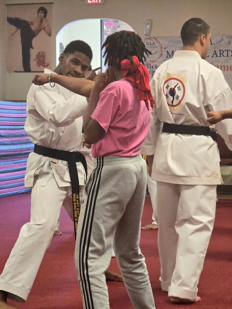 A black belt instructor showing a student how to break a hold at close range.